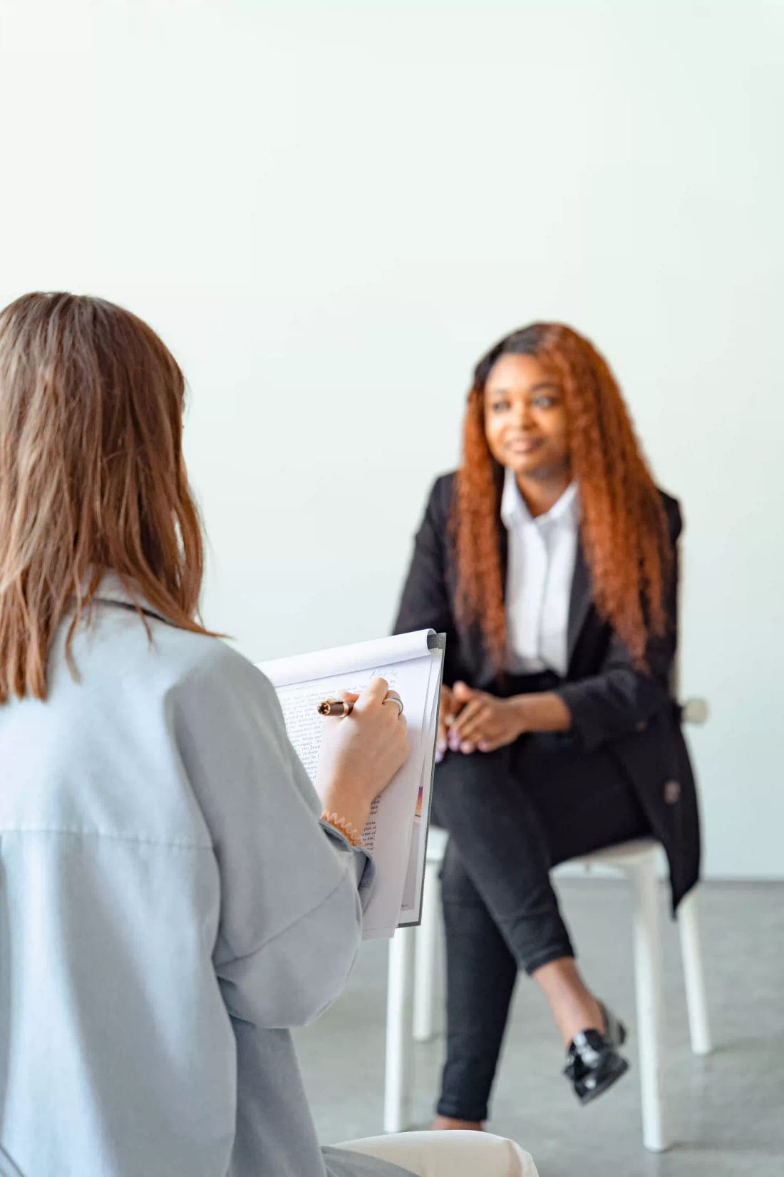 A Birchwood Leadership practitioner taking notes while debriefing assessment results with a client seated across from her