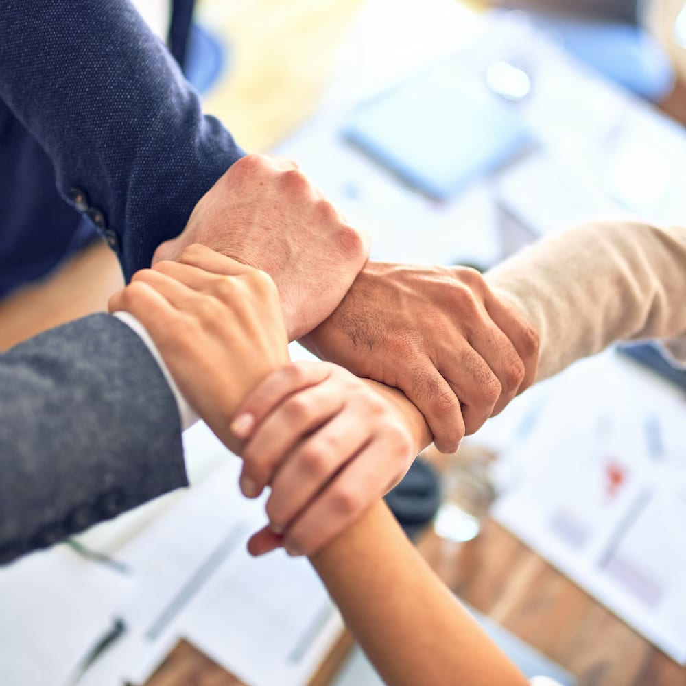 Colleagues joining hands across a meeting table