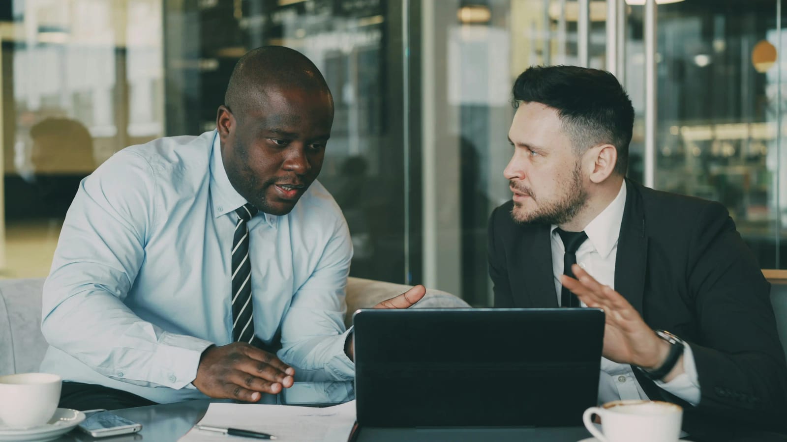 Two business colleagues in an unhurried, focused conversation over a laptop in a modern office