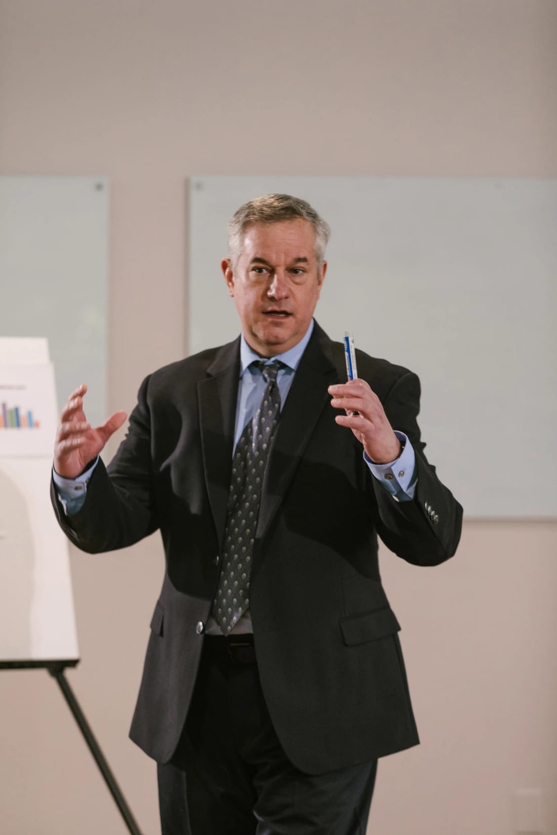 A leader speaking with quiet confidence, gesturing as he presents to a room
