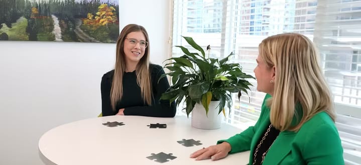 Two colleagues in conversation across a table in a bright office