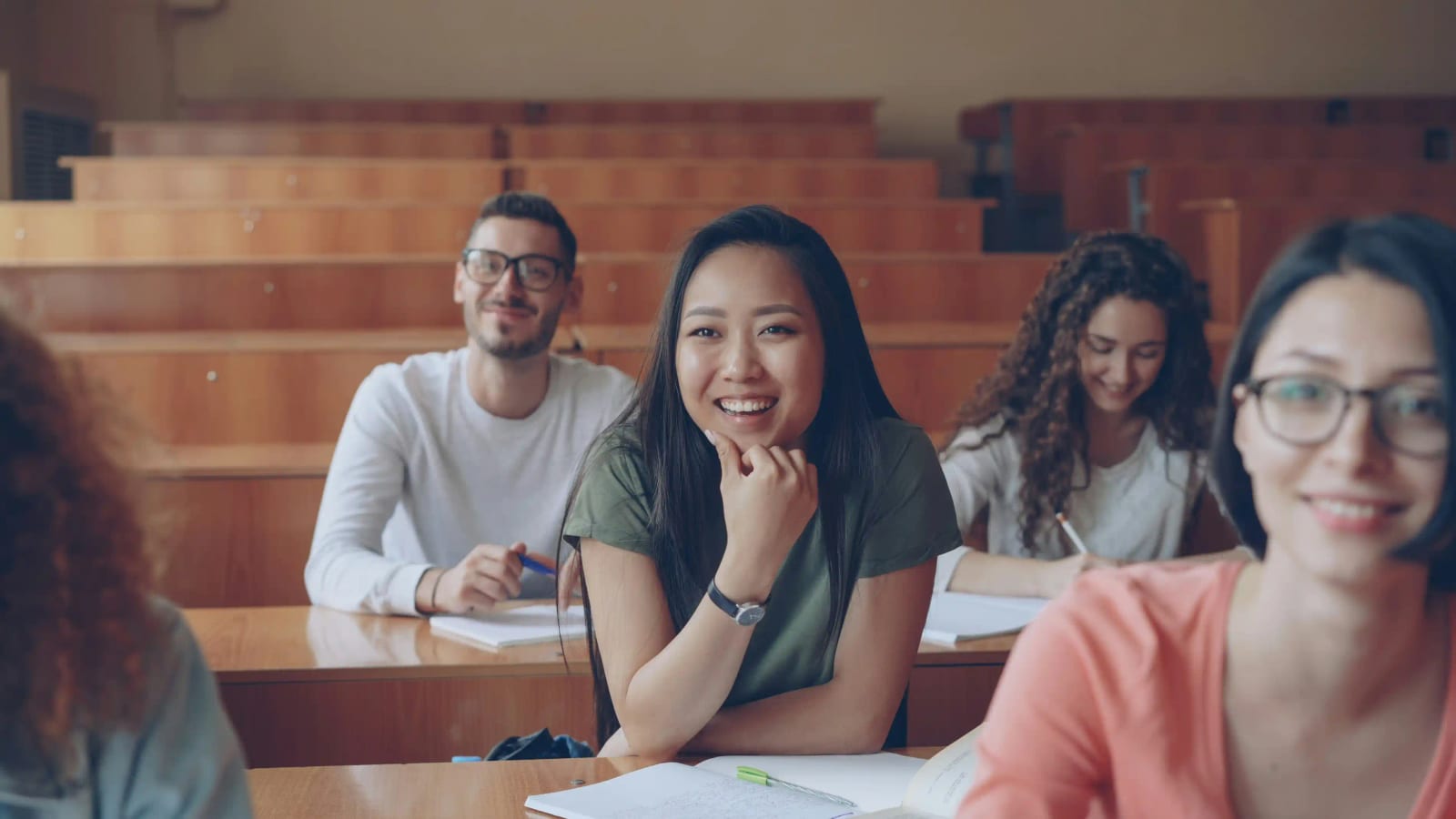 A group of diverse students smiling in a bright lecture hall