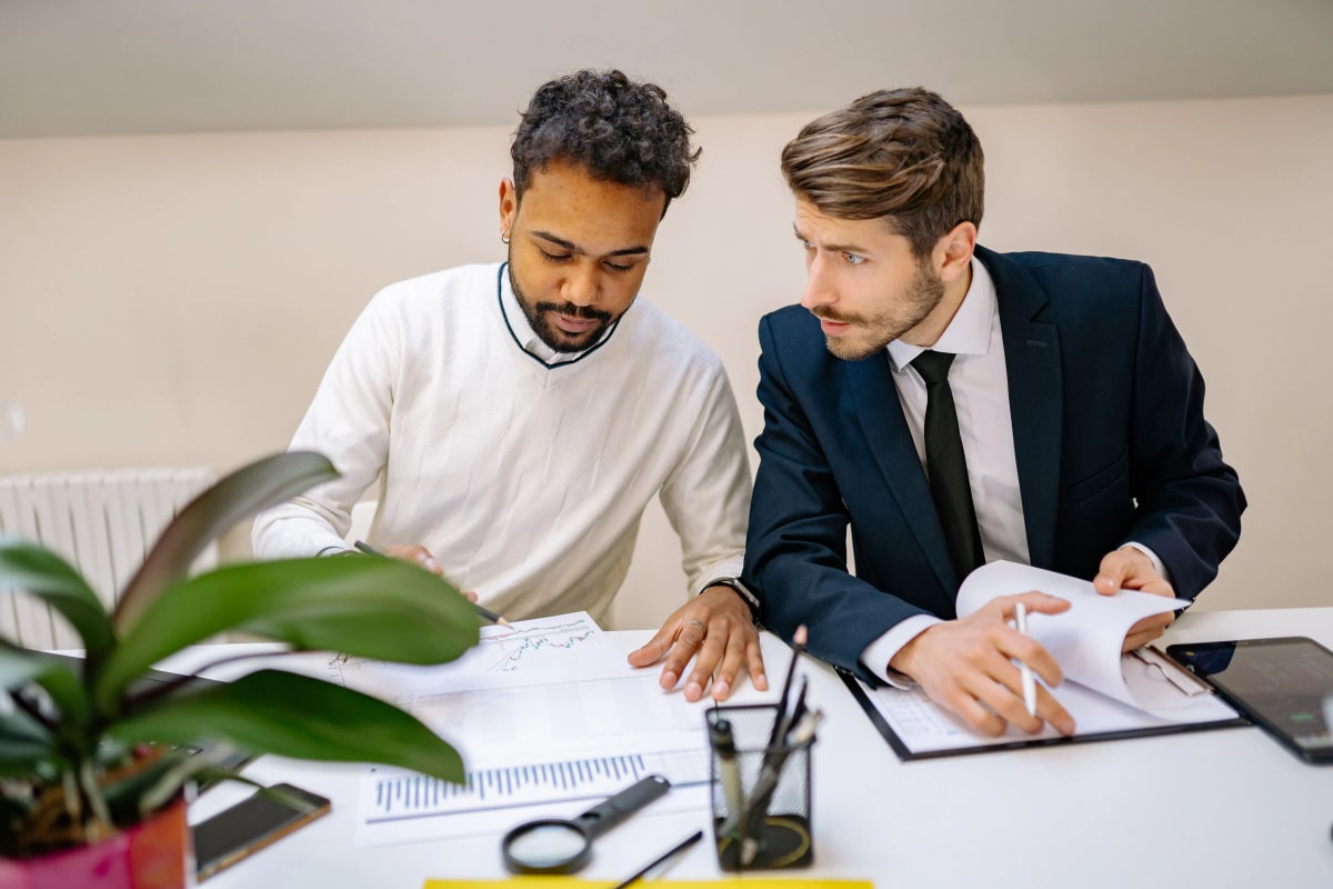 Two colleagues reviewing charts and reports at a desk