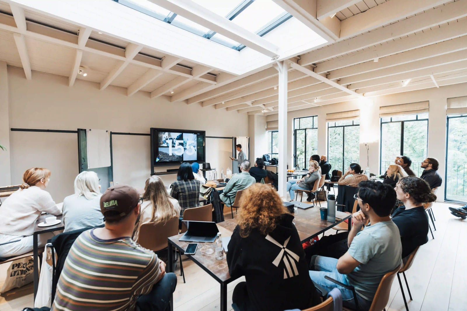 A facilitator leading an interactive workshop for a room of seated participants in a bright, open studio